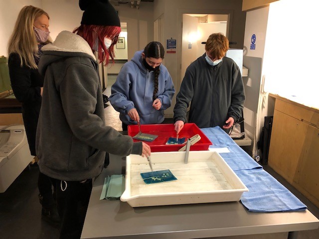 Colour photo of a group of young people processing photos/