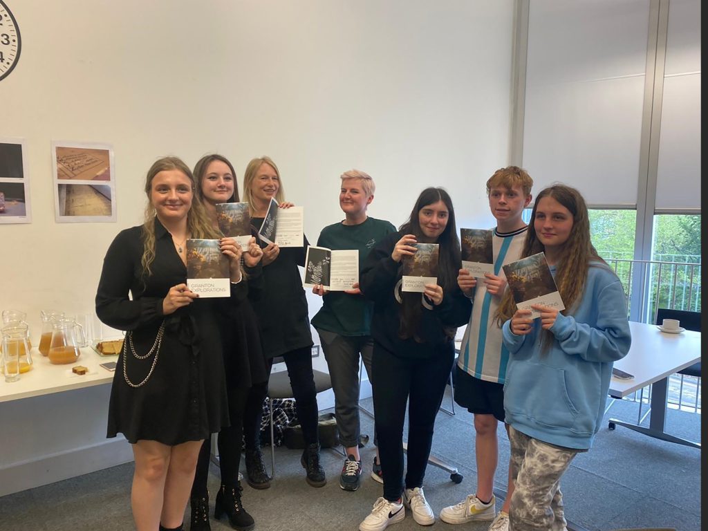 Colour photo of a group of seven young people holding, each holding  a leaflet.